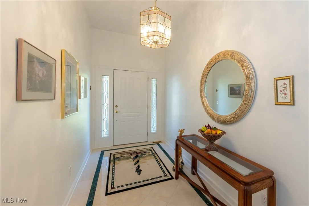 Entryway featuring baseboards, a chandelier, a towering ceiling, and light tile patterned floors