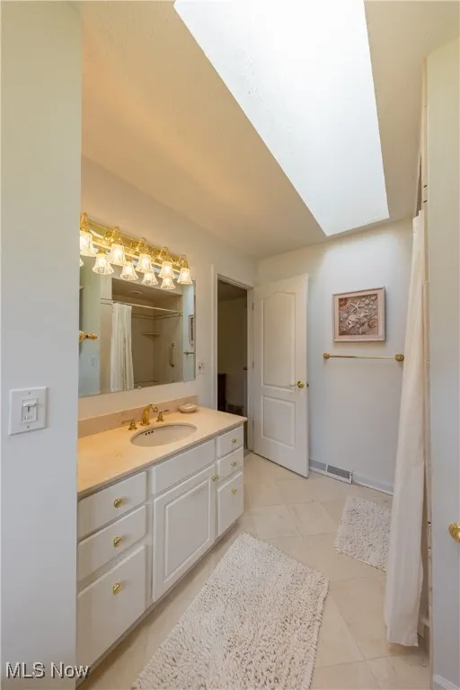 Bathroom with tile patterned floors, vanity, and baseboards
