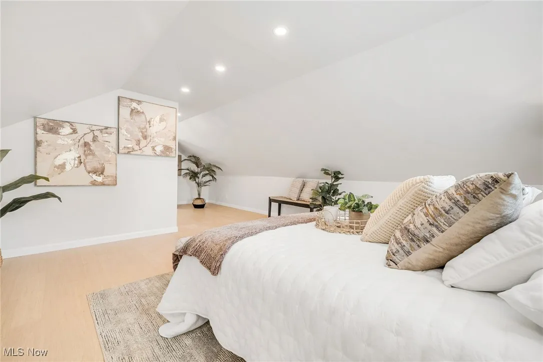 Bedroom with wood finished floors, lofted ceiling, recessed lighting, and baseboards