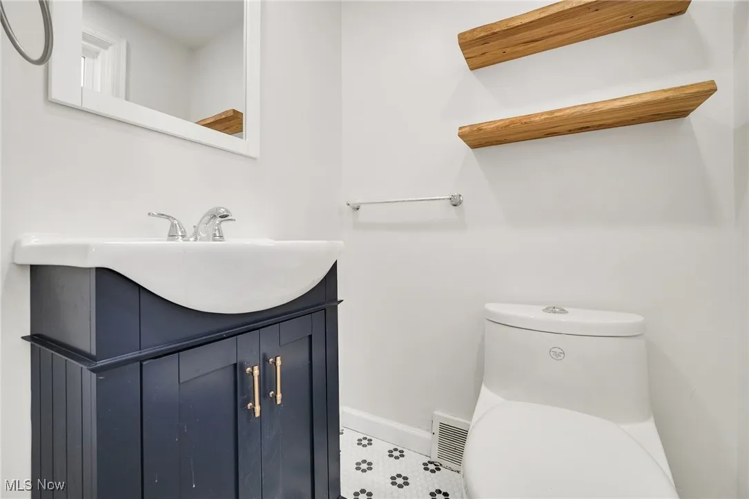 Half bath with toilet, vanity, and baseboards