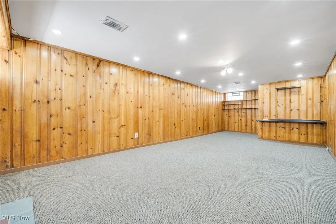 Below grade area with wood walls, recessed lighting, and carpet flooring