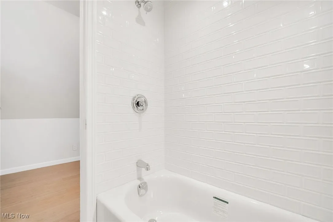 Bathroom with wood finished floors, shower / tub combination, and baseboards