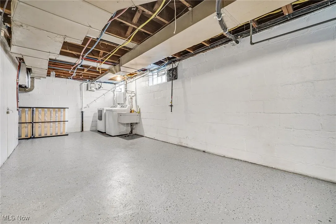 Unfinished below grade area featuring washing machine and dryer and concrete block wall