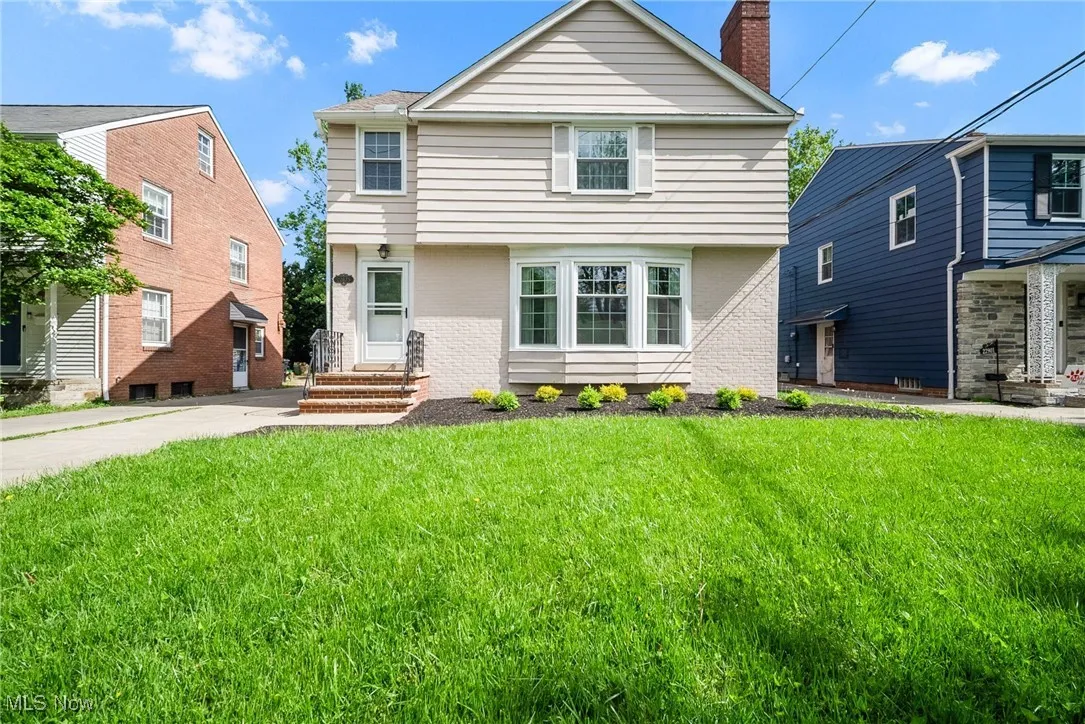 Colonial-style house with brick siding, a front yard, and a chimney