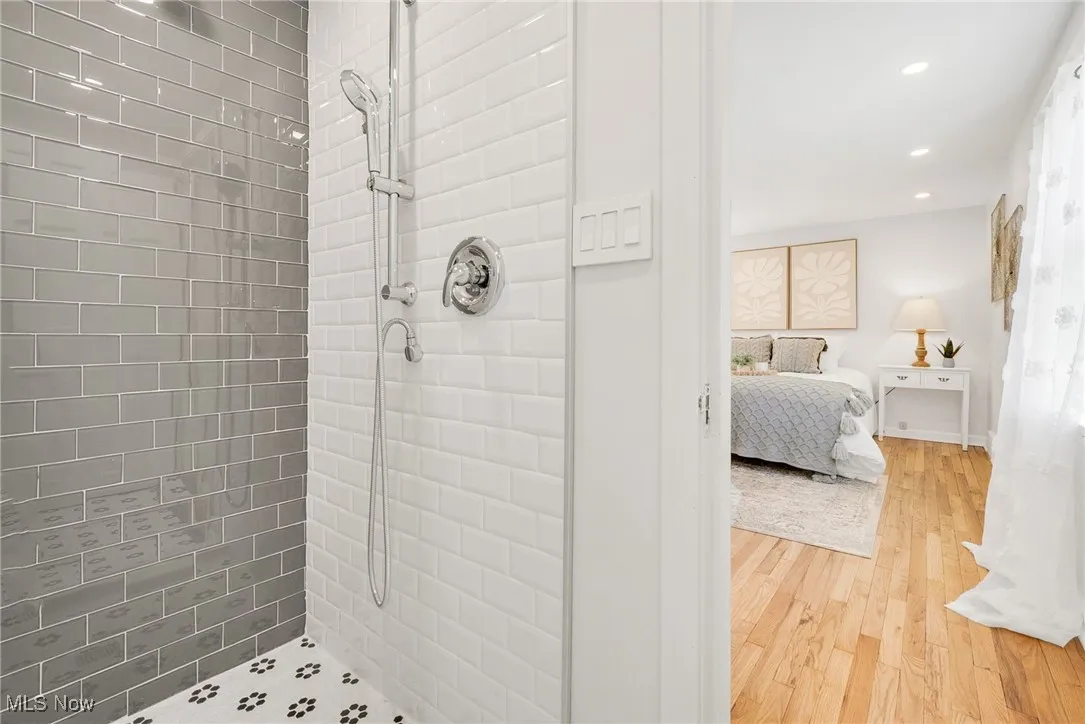 Bathroom with connected bathroom, a tile shower, wood finished floors, and recessed lighting