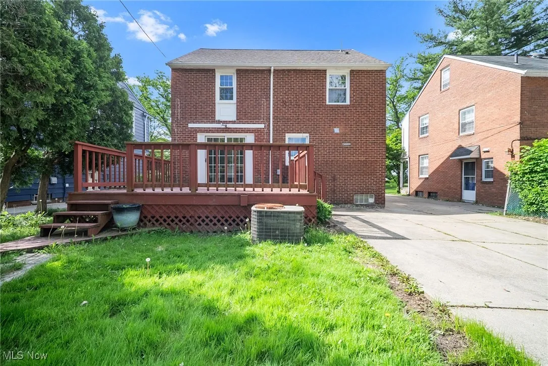 Rear view of property with cooling unit, brick siding, and a wooden deck