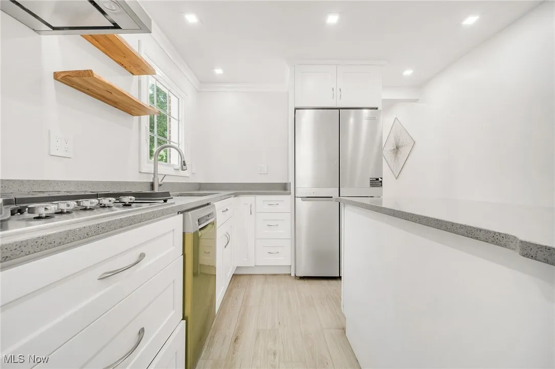 Kitchen featuring open shelves, a sink, stainless steel appliances, white cabinets, and crown molding