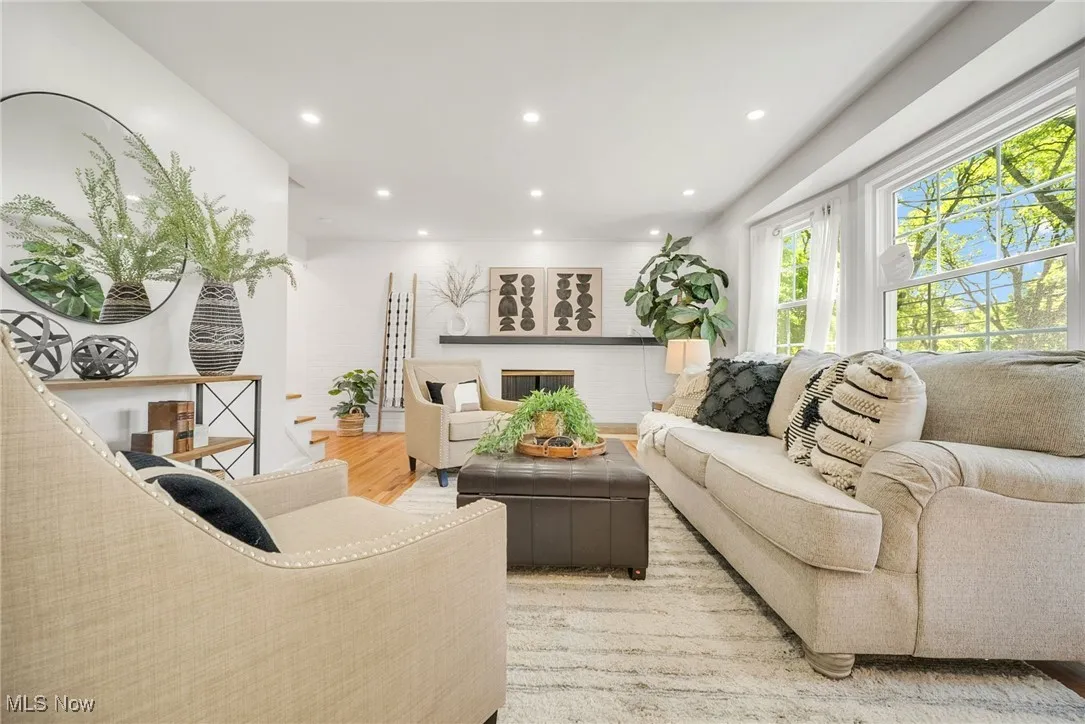 Living area with healthy amount of natural light, recessed lighting, light wood-style floors, and a glass covered fireplace