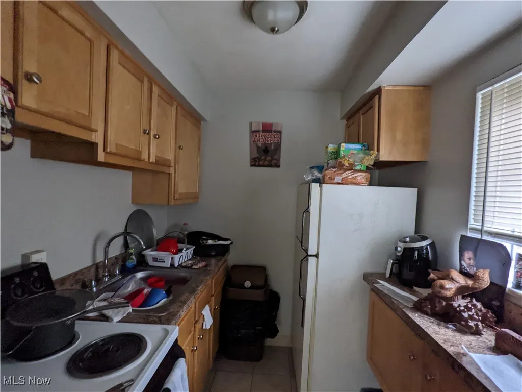 Kitchen with white appliances, a sink, plenty of natural light, and light tile patterned flooring