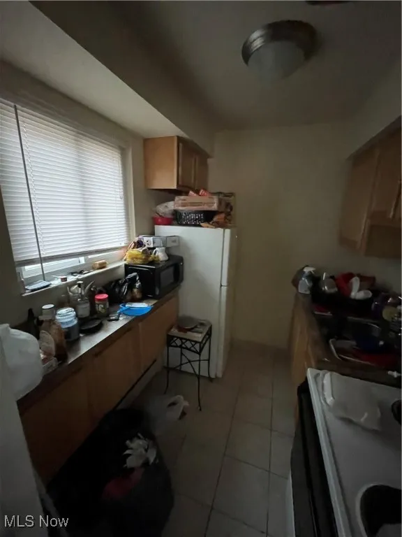 Kitchen featuring range, light tile patterned floors, and fridge