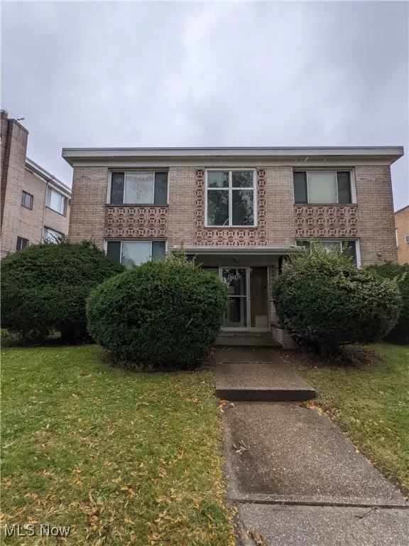 Townhome / multi-family property with a front lawn and brick siding