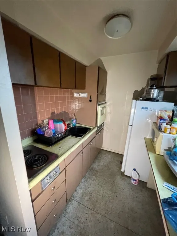 Kitchen featuring backsplash, light countertops, a sink, stovetop, and oven