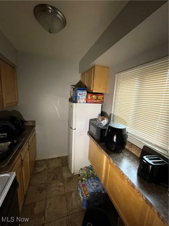 Kitchen with stove, dark countertops, refrigerator, and a sink