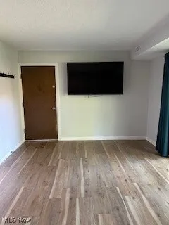 Unfurnished room with wood finished floors and baseboards