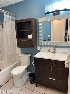 Bathroom with tile patterned floors, a textured ceiling, toilet, vanity, and shower / tub combo