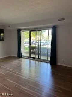 Unfurnished room with baseboards, wood finished floors, and a textured ceiling
