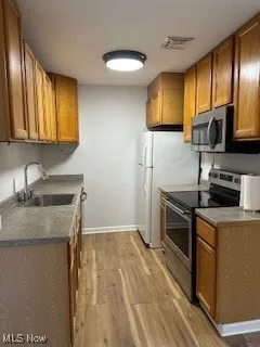 Kitchen with range, a sink, light wood-type flooring, and brown cabinetry
