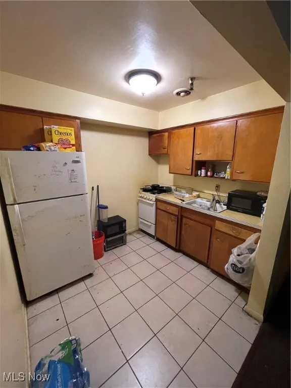 Kitchen featuring gas range gas stove, refrigerator, brown cabinets, and a sink