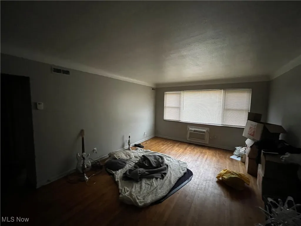 Living area featuring a wall mounted AC, wood finished floors, and baseboards