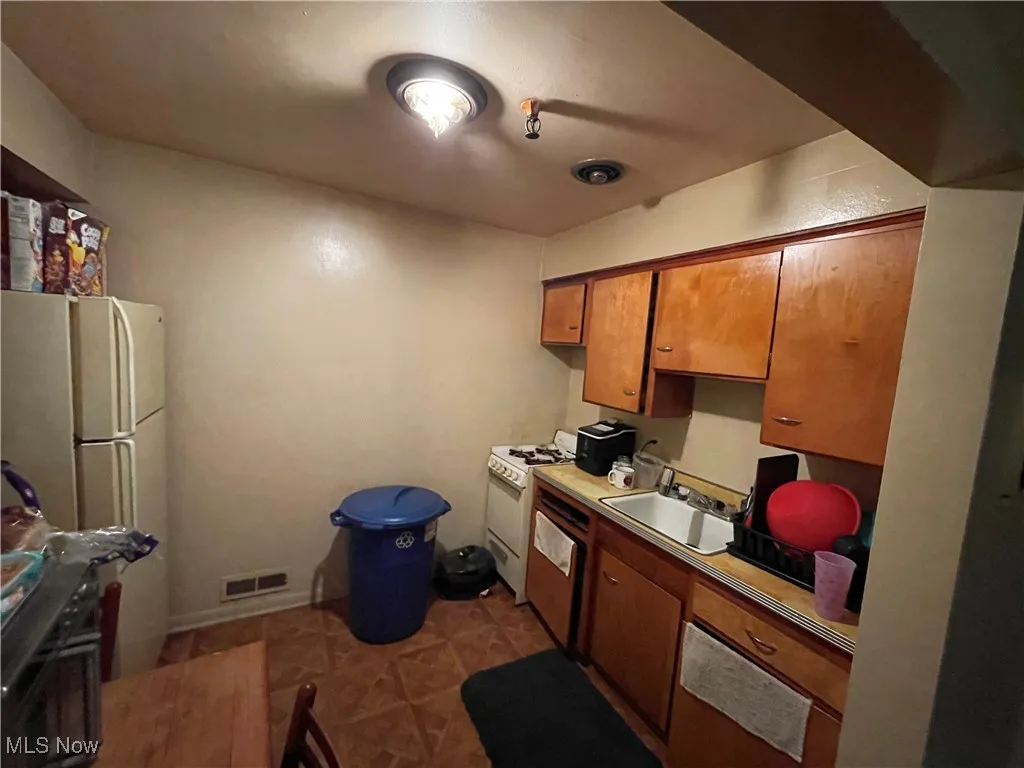 Kitchen with a sink, white appliances, brown cabinets, and light countertops
