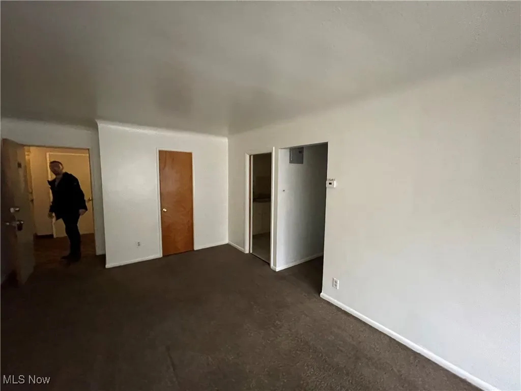 Unfurnished bedroom with a closet, baseboards, and dark carpet
