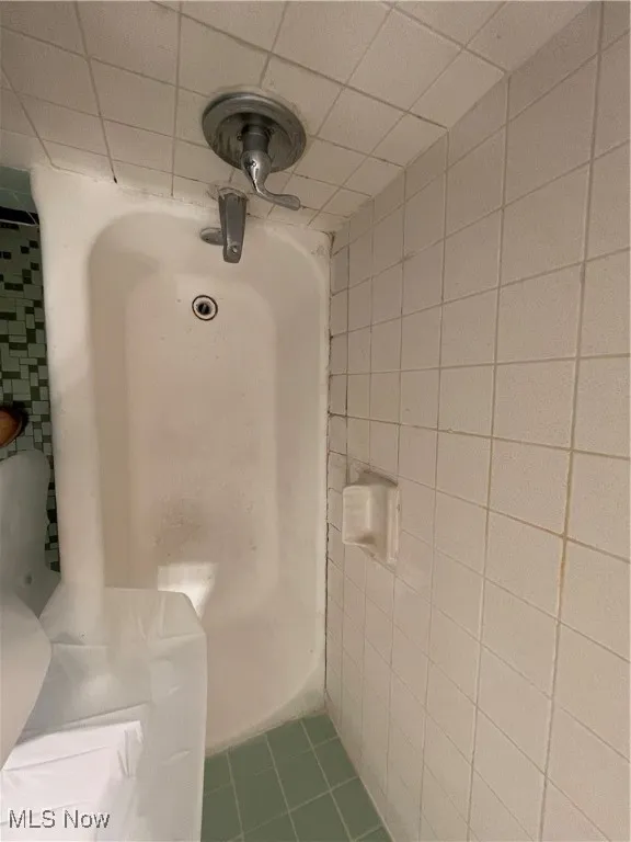 Full bathroom with tile patterned floors and tile walls