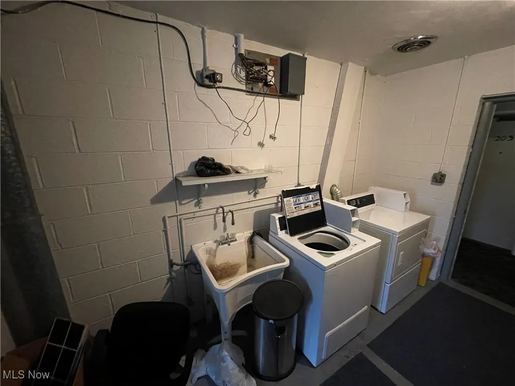 Washroom featuring concrete block wall and washing machine and dryer