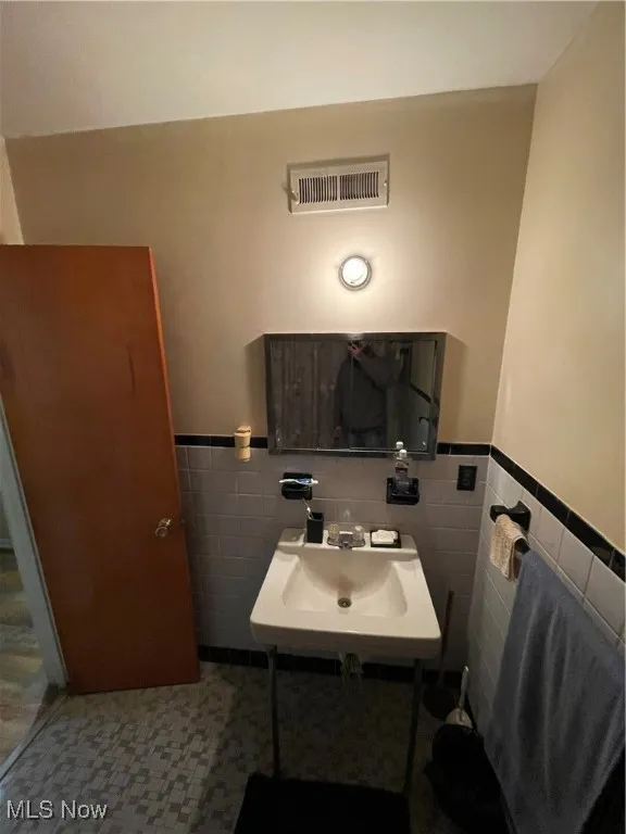Bathroom featuring tile walls, a wainscoted wall, a sink, and pet washing station
