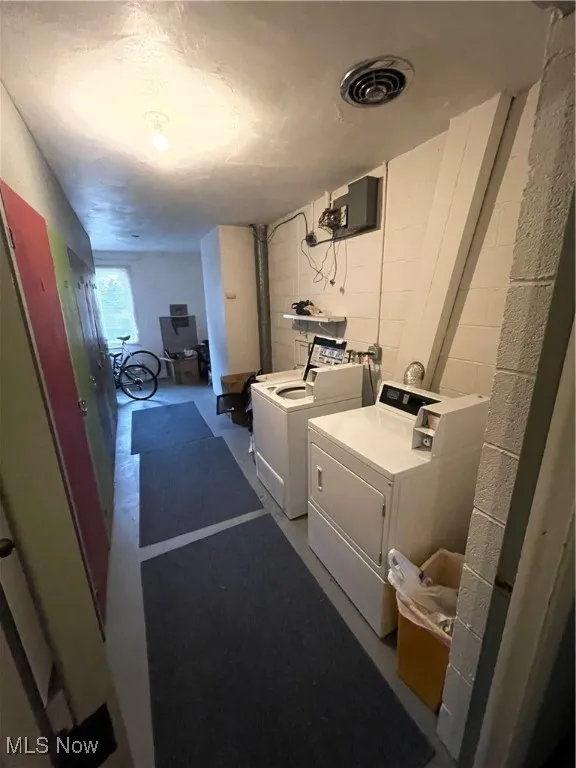 Laundry area featuring washer and clothes dryer and concrete block wall