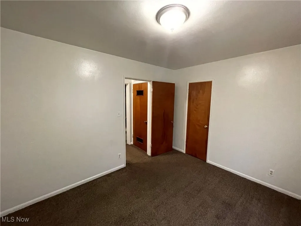 Empty room with dark colored carpet and baseboards
