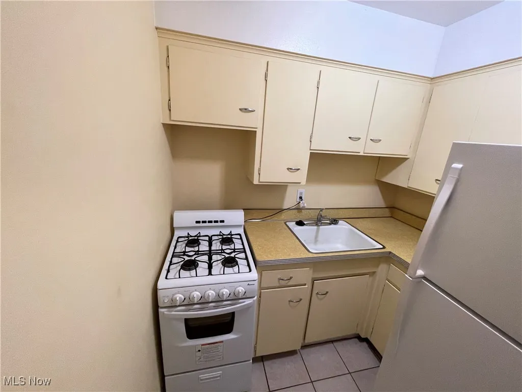 Kitchen featuring white appliances, a sink, light countertops, and light tile patterned floors