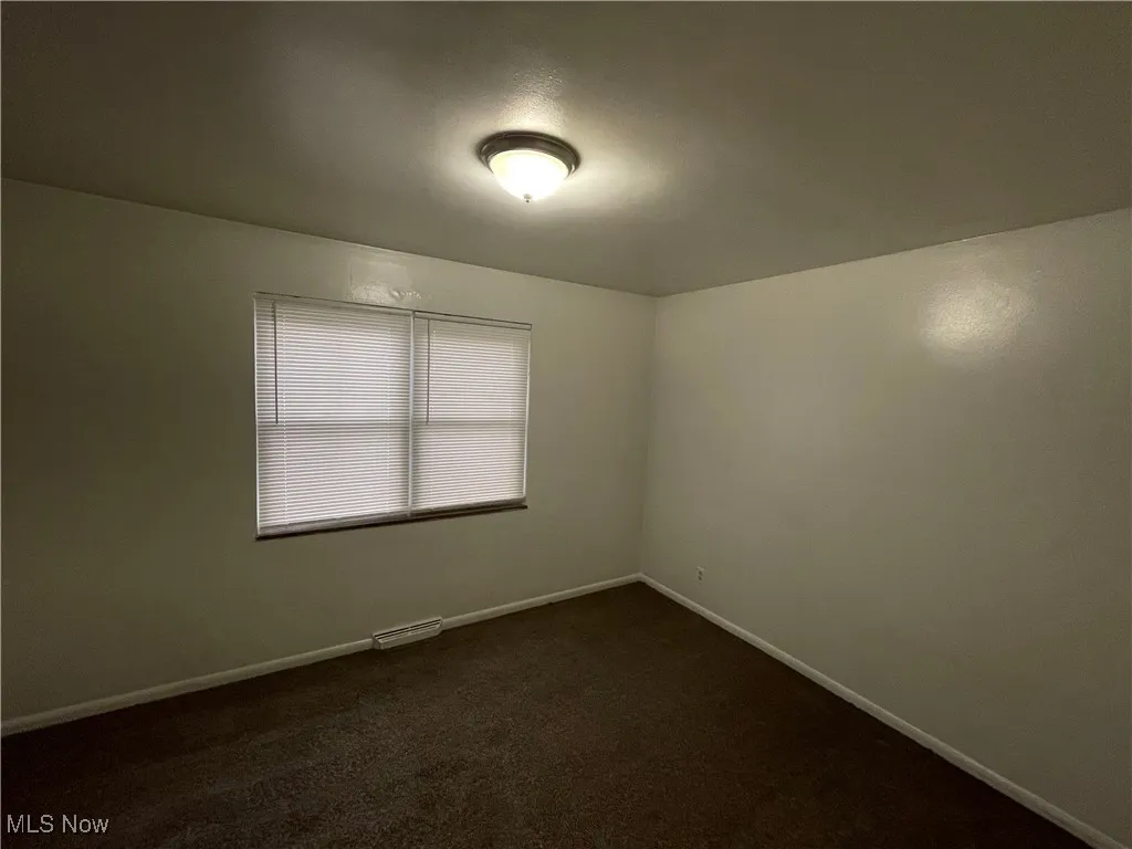 Unfurnished room with baseboards and dark carpet