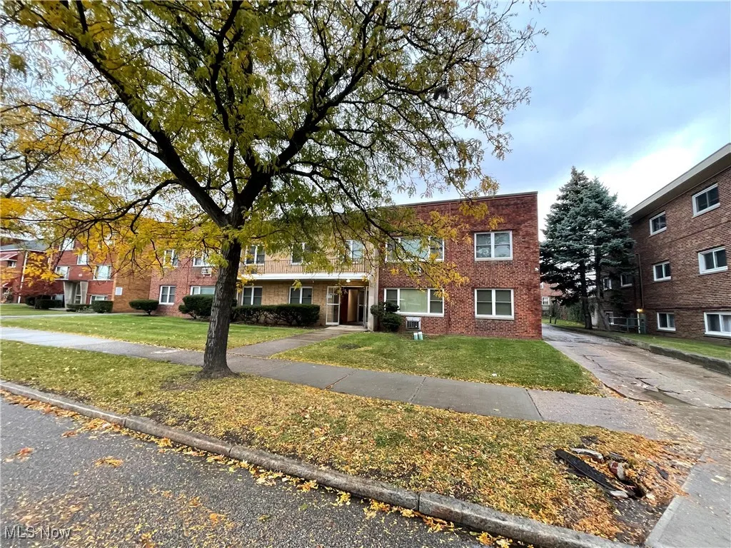 Townhome / multi-family property featuring a front yard and brick siding