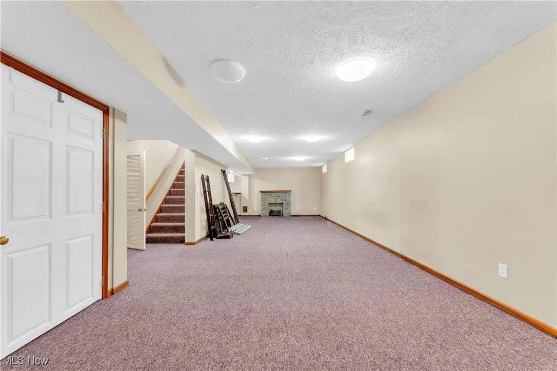 Finished basement featuring a fireplace, baseboards, carpet floors, and a textured ceiling