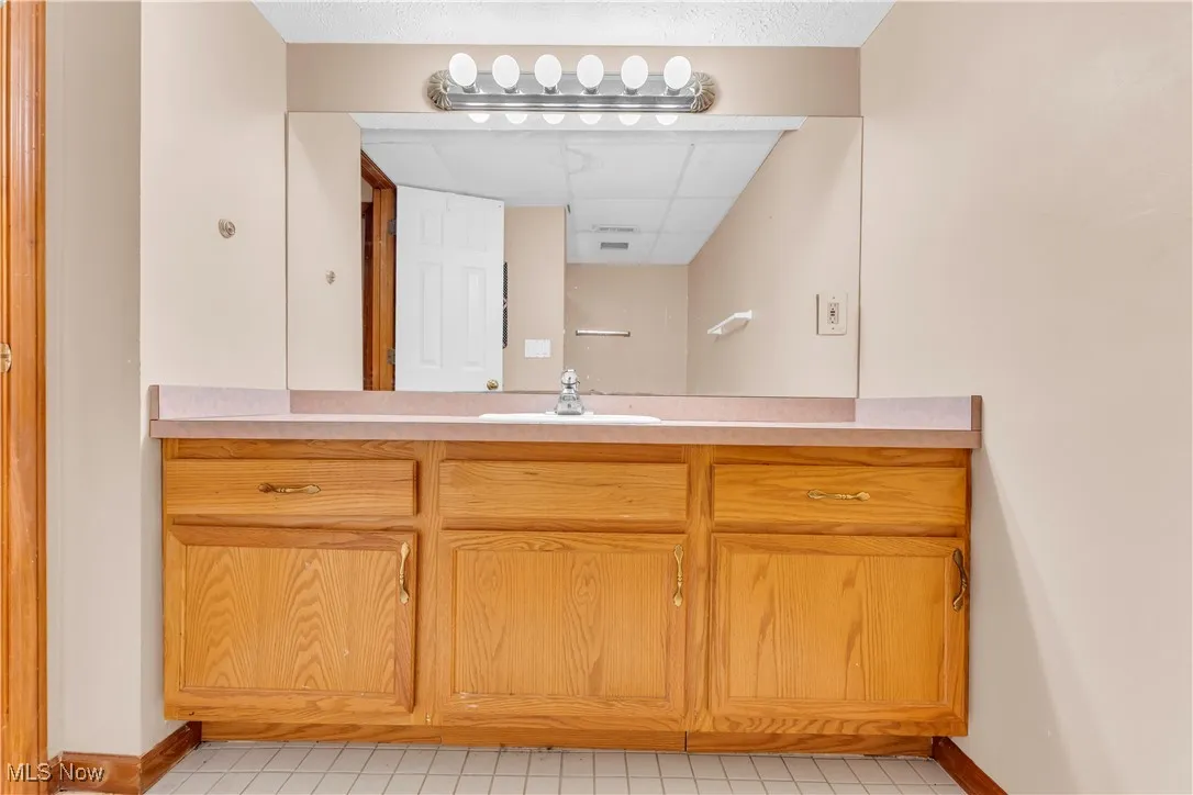 Bathroom featuring baseboards, vanity, and tile patterned flooring