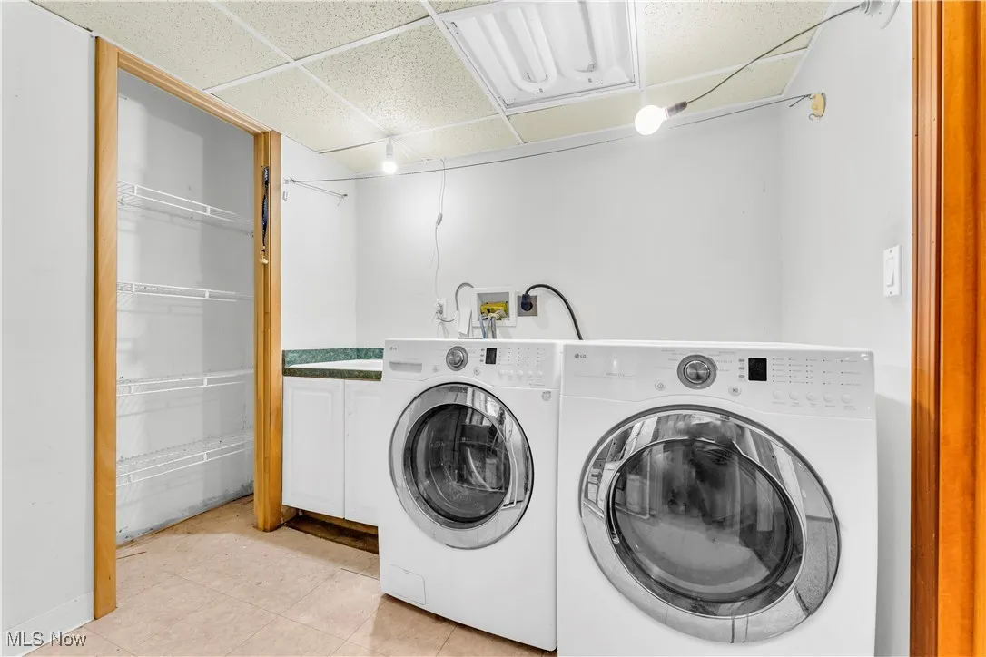 Laundry room with cabinet space, separate washer and dryer, and light tile patterned flooring