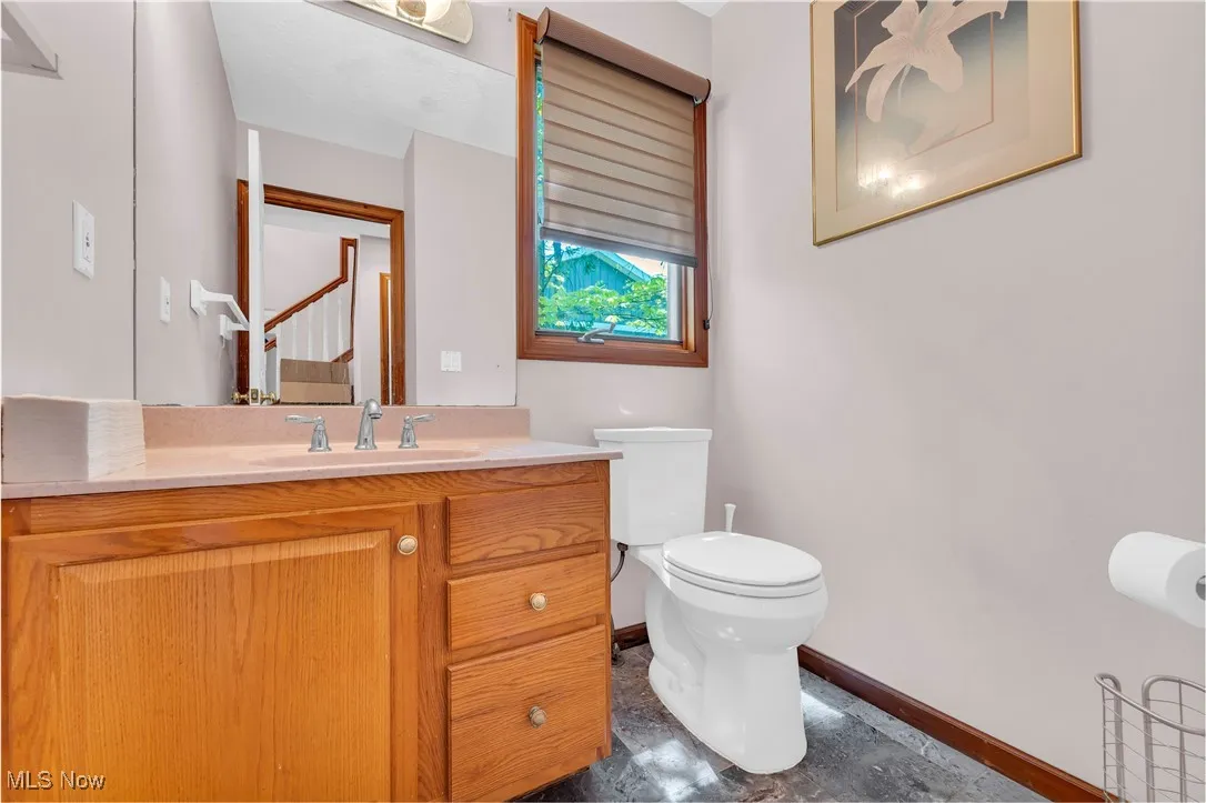 Half bath with baseboards, toilet, and vanity