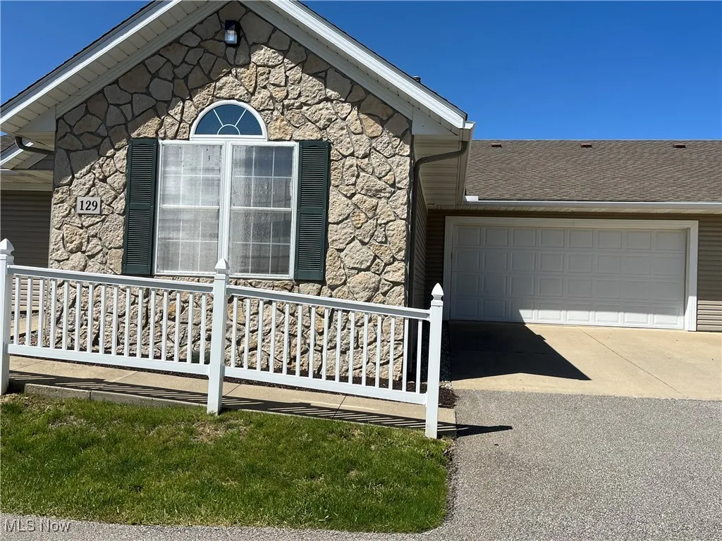 View of side of property with stone siding, concrete driveway, and an attached garage
