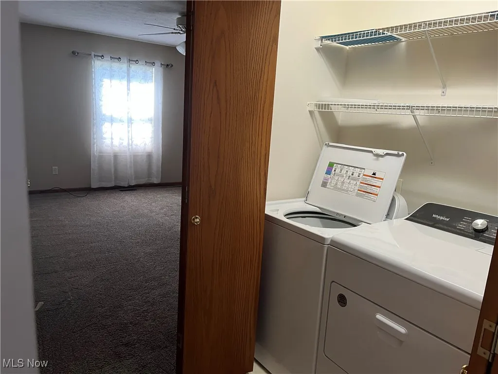 Washroom featuring light colored carpet, washing machine and dryer, a ceiling fan, and baseboards