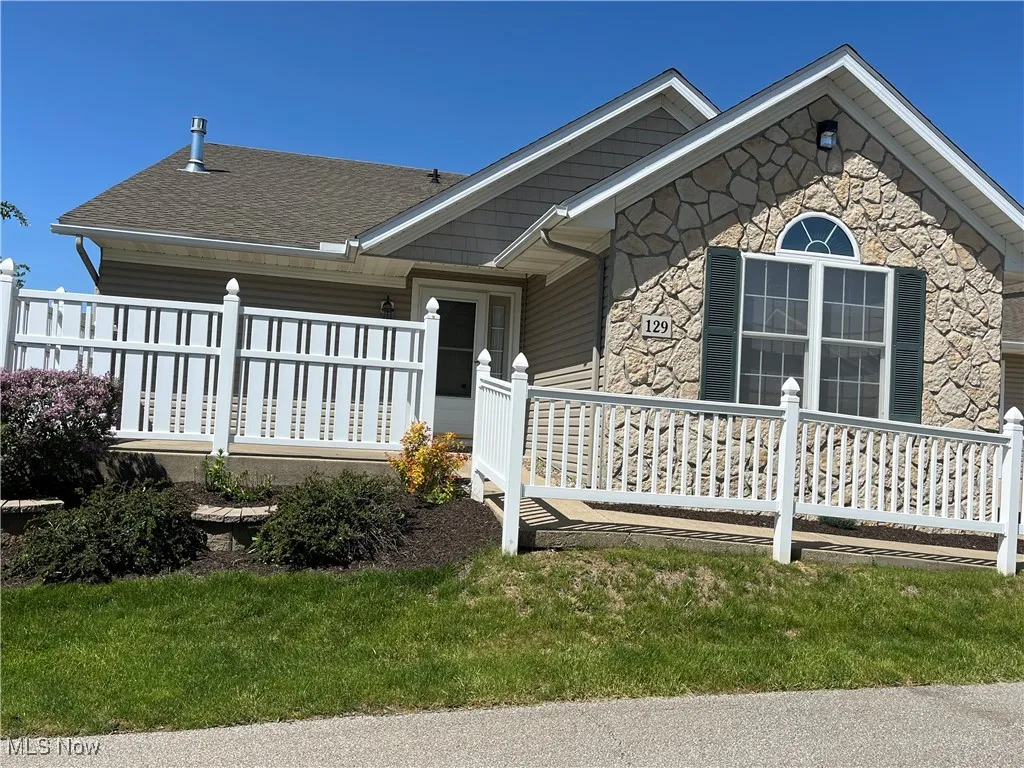 View of front of home with stone siding and roof with shingles