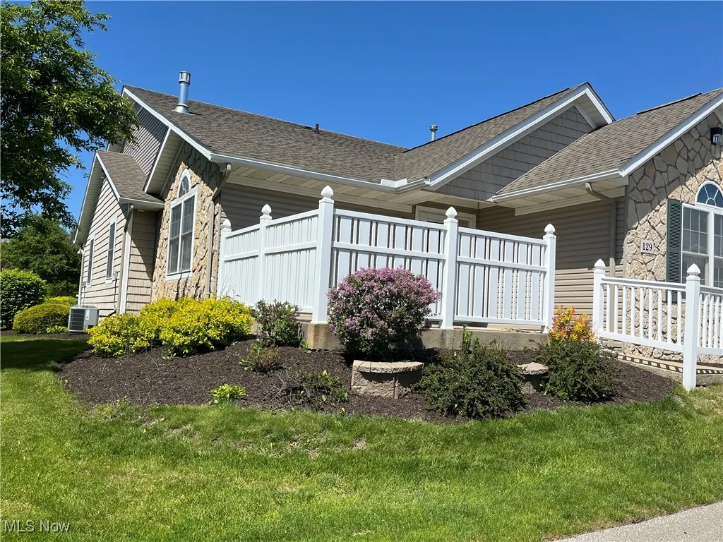 View of property exterior with cooling unit, a shingled roof, and stone siding