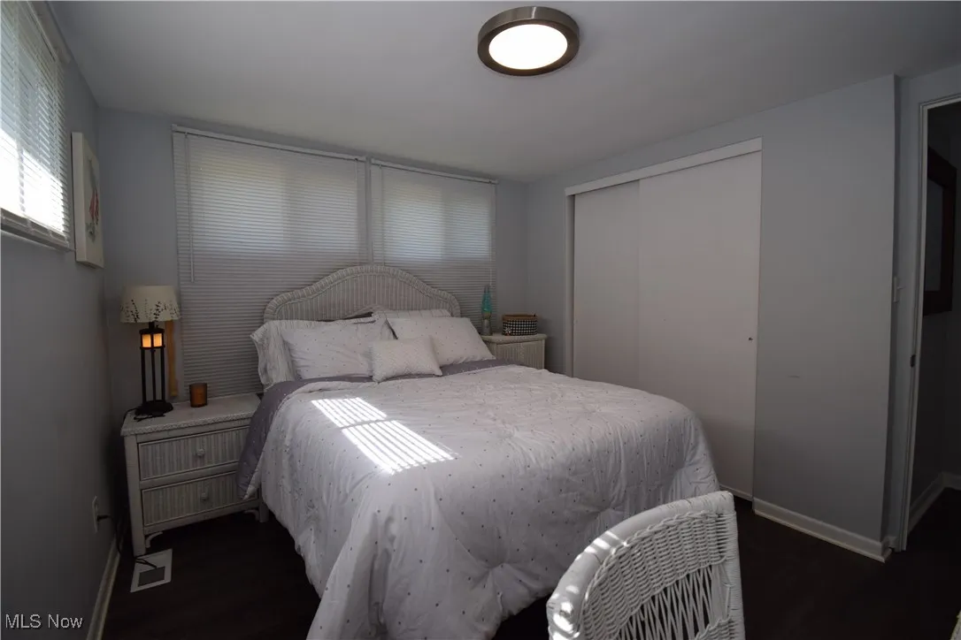 Bedroom with wood finished floors, baseboards, and a closet