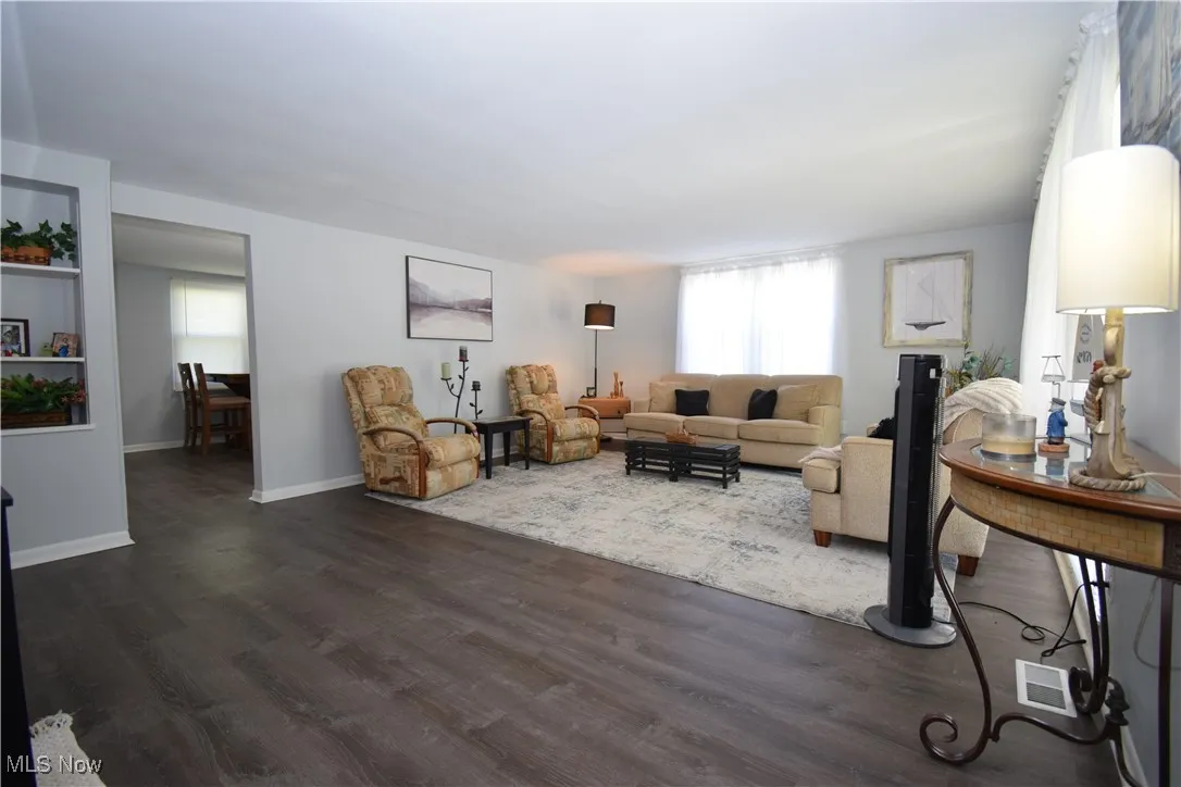 Living room featuring dark wood-style flooring and baseboards