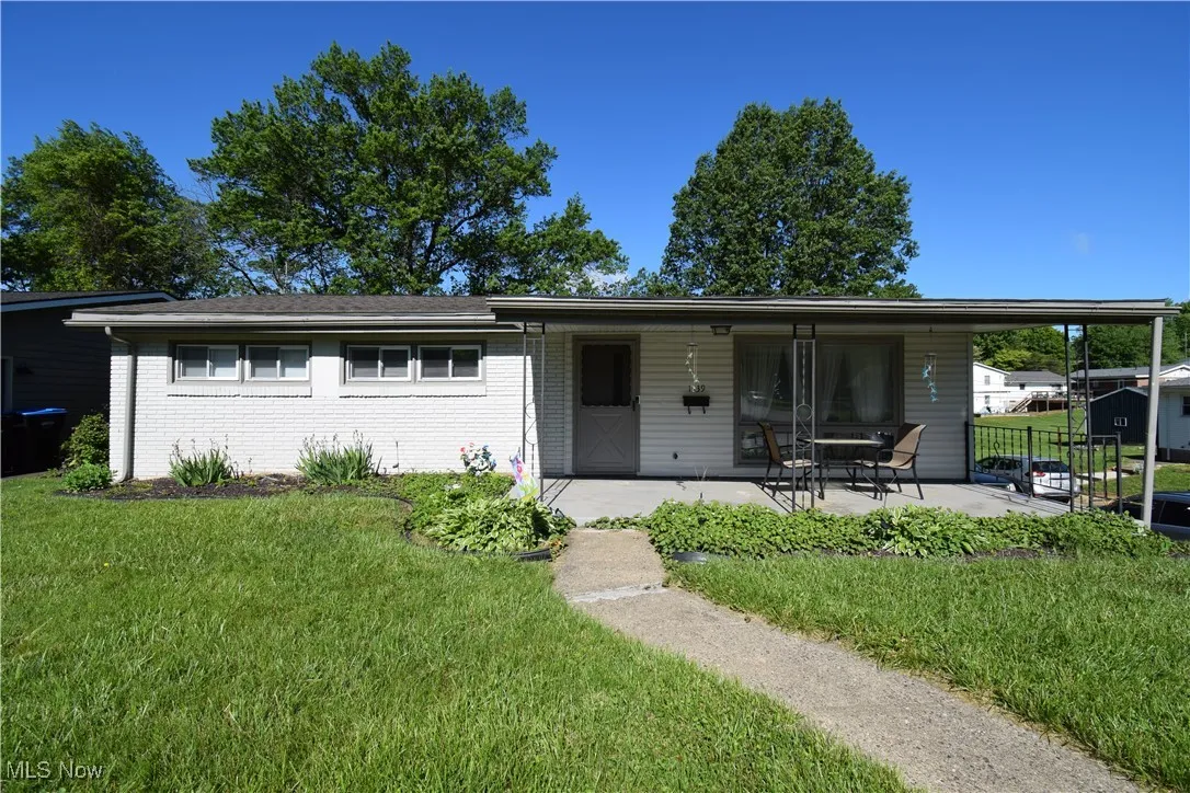 View of front of house featuring a front lawn, a patio, and brick siding