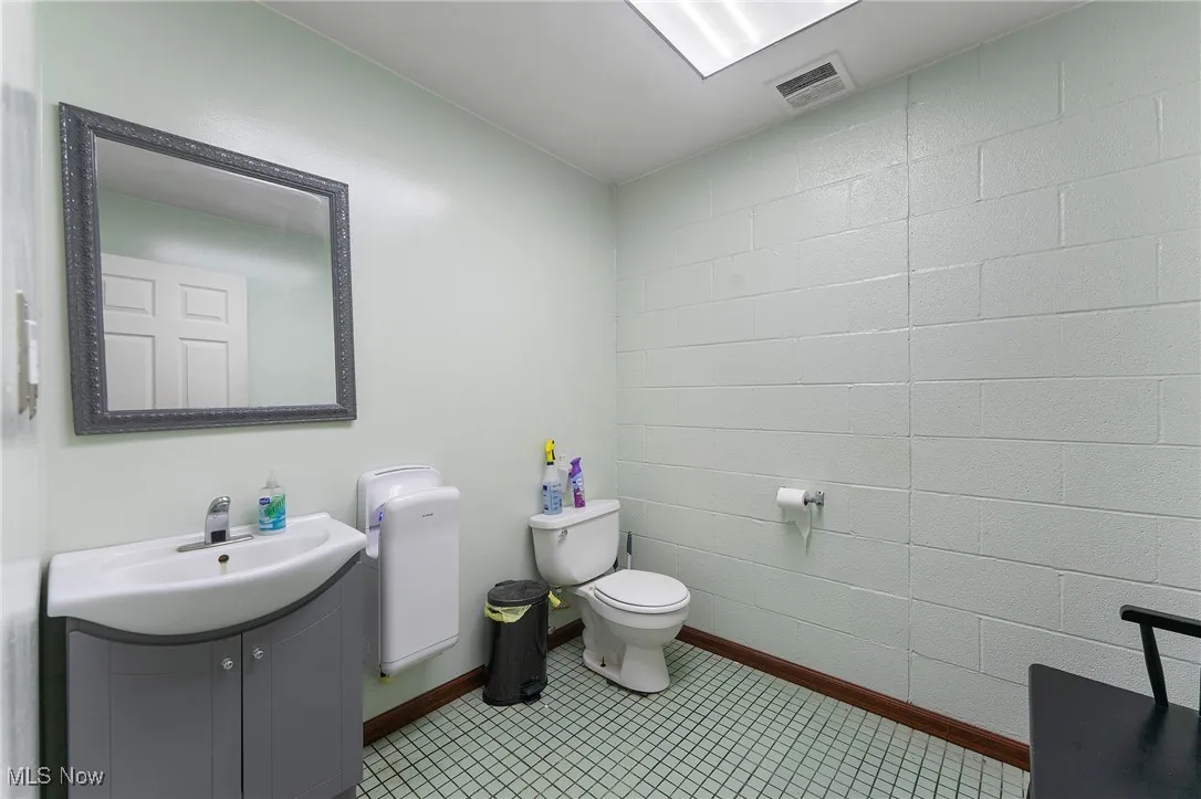 Bathroom with toilet, baseboards, vanity, and tile patterned floors