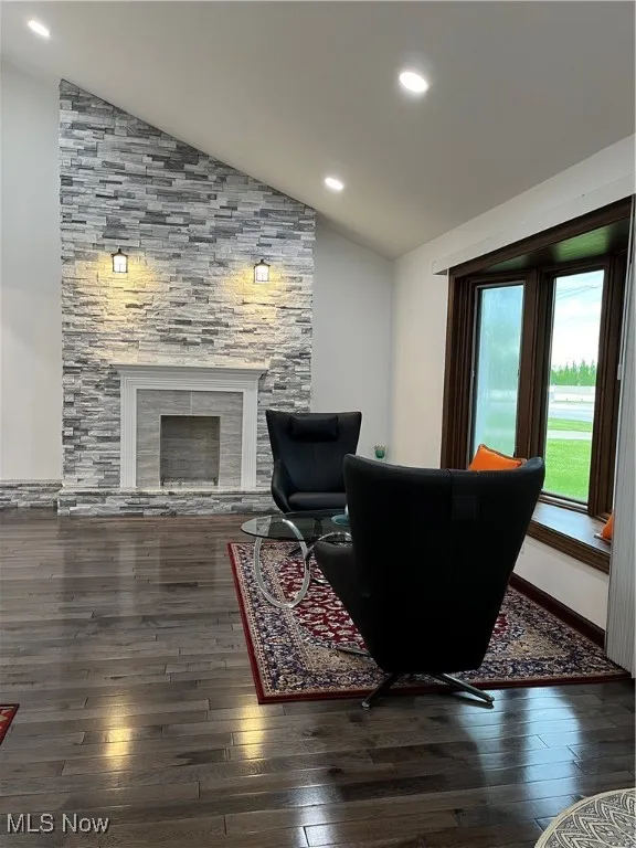 Living room featuring vaulted ceiling, wood-type flooring, a fireplace, and recessed lighting
