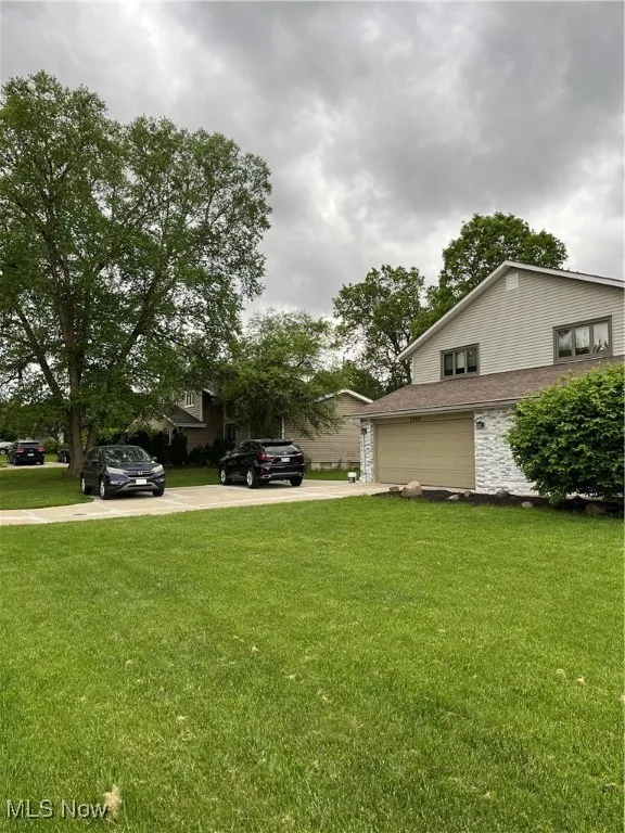 View of grassy yard with driveway and an attached garage
