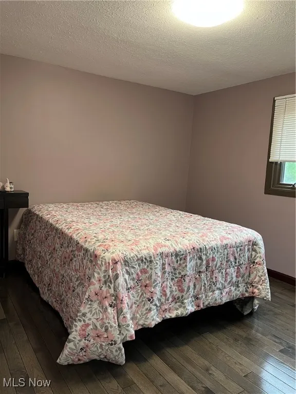 Bedroom with dark wood-style flooring and baseboards