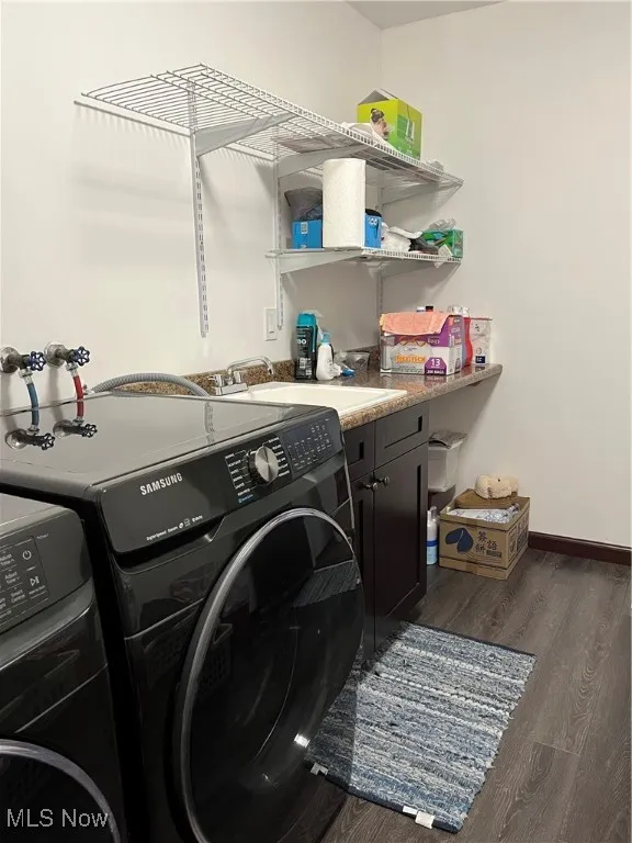 Laundry area featuring washer and dryer, cabinet space, and wood finished floors