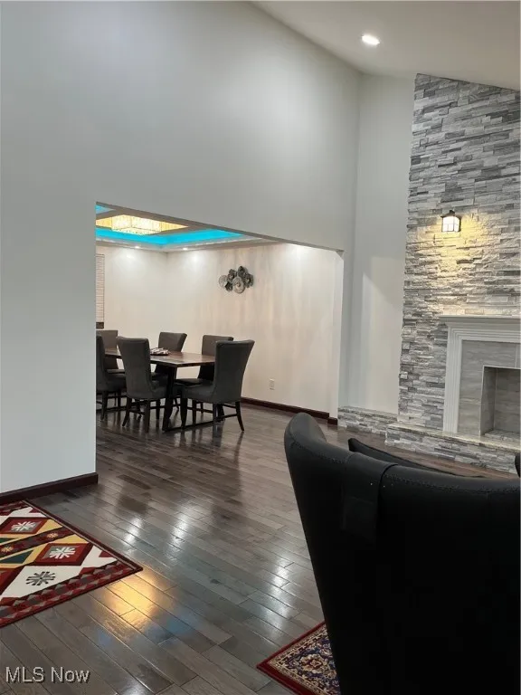 Living area with high vaulted ceiling, hardwood / wood-style flooring, baseboards, and a fireplace